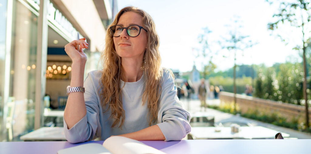 Casual woman sitting at table and taking notes in notebook .on the cafe terrace